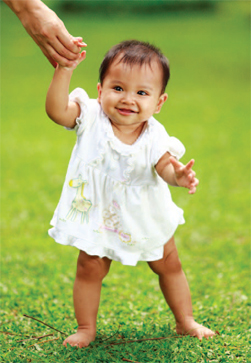 baby walking holding someone's hand for support