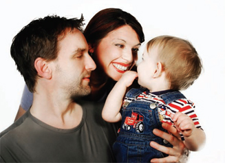 man and woman holding and smiling at toddler