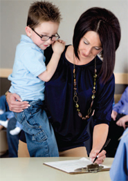 woman holding a child while writing on a clip board